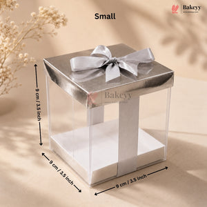 Small clear cake stand with silver bow and dimensions on a beige background