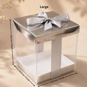 Large clear cake stand with silver bow and dimensions on a beige background