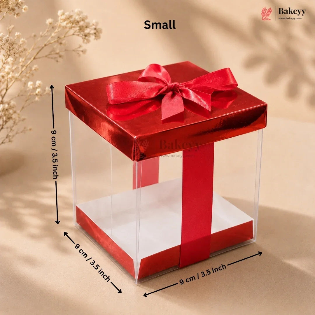 Small red gift box with a clear front and a red ribbon on a beige background