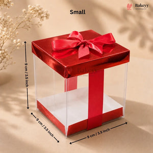 Small red gift box with a clear front and a red ribbon on a beige background