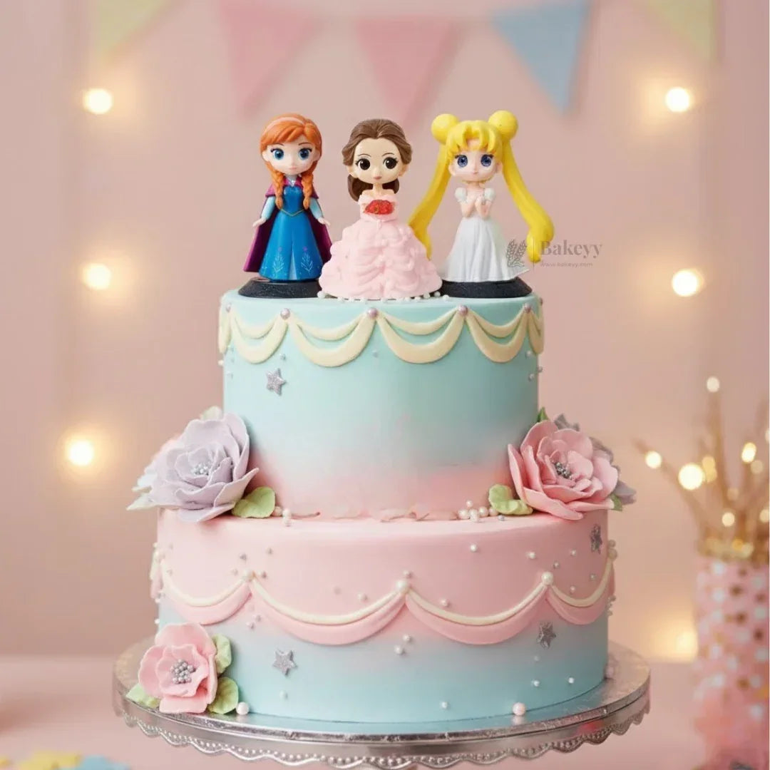 Princess themed doll toppers on pastel pink and blue two-tier cake with floral decorations, Bakeyy
