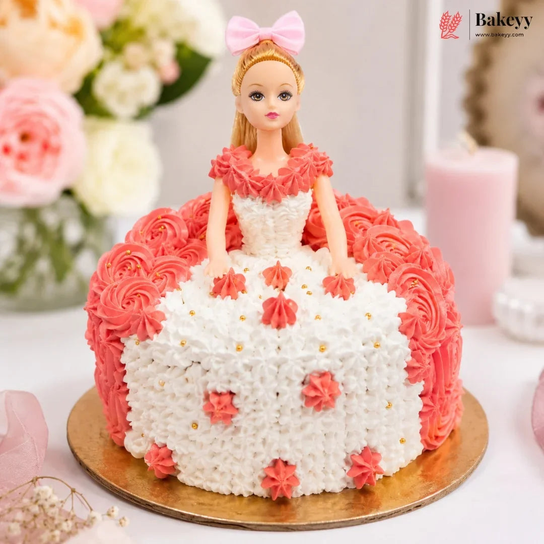 Barbie doll cake with pink and white frosting on a wooden board, surrounded by flowers and candles.