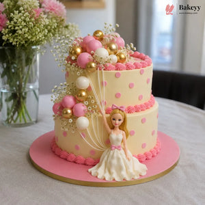 Decorative cake with pink and gold polka dots, balloons, and a Barbie figure on a table.
