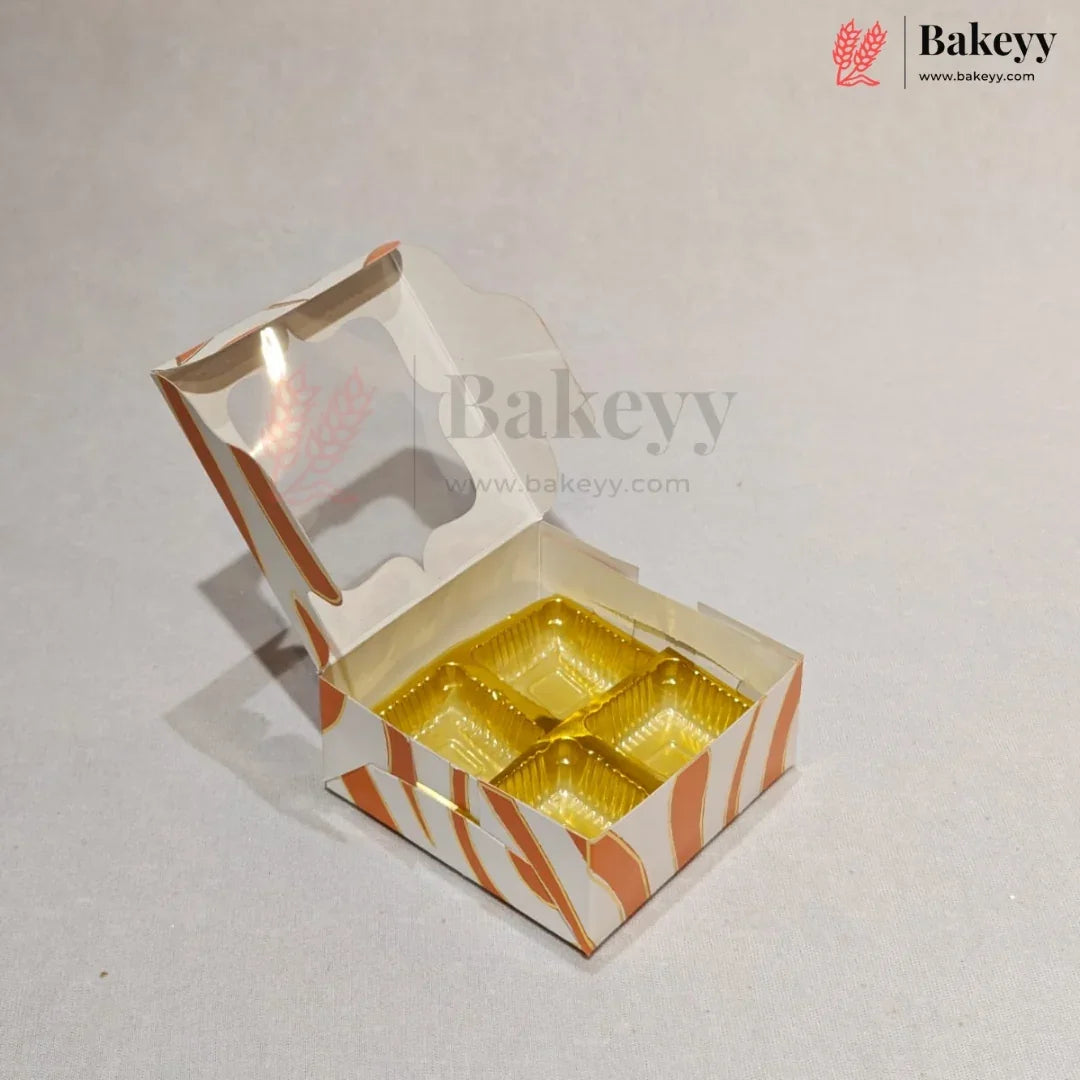 An open custom bakery box with a hinged lid, featuring orange and white wavy stripes and a clear window, containing four gold-colored round cupcake liners, set against a light gray background.