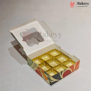 An open bakery box with a hinged lid, featuring a clear window on the lid and nine gold-colored cup-like compartments on the bottom. The box has a decorative pattern on the sides with red, orange, green, and black shapes.