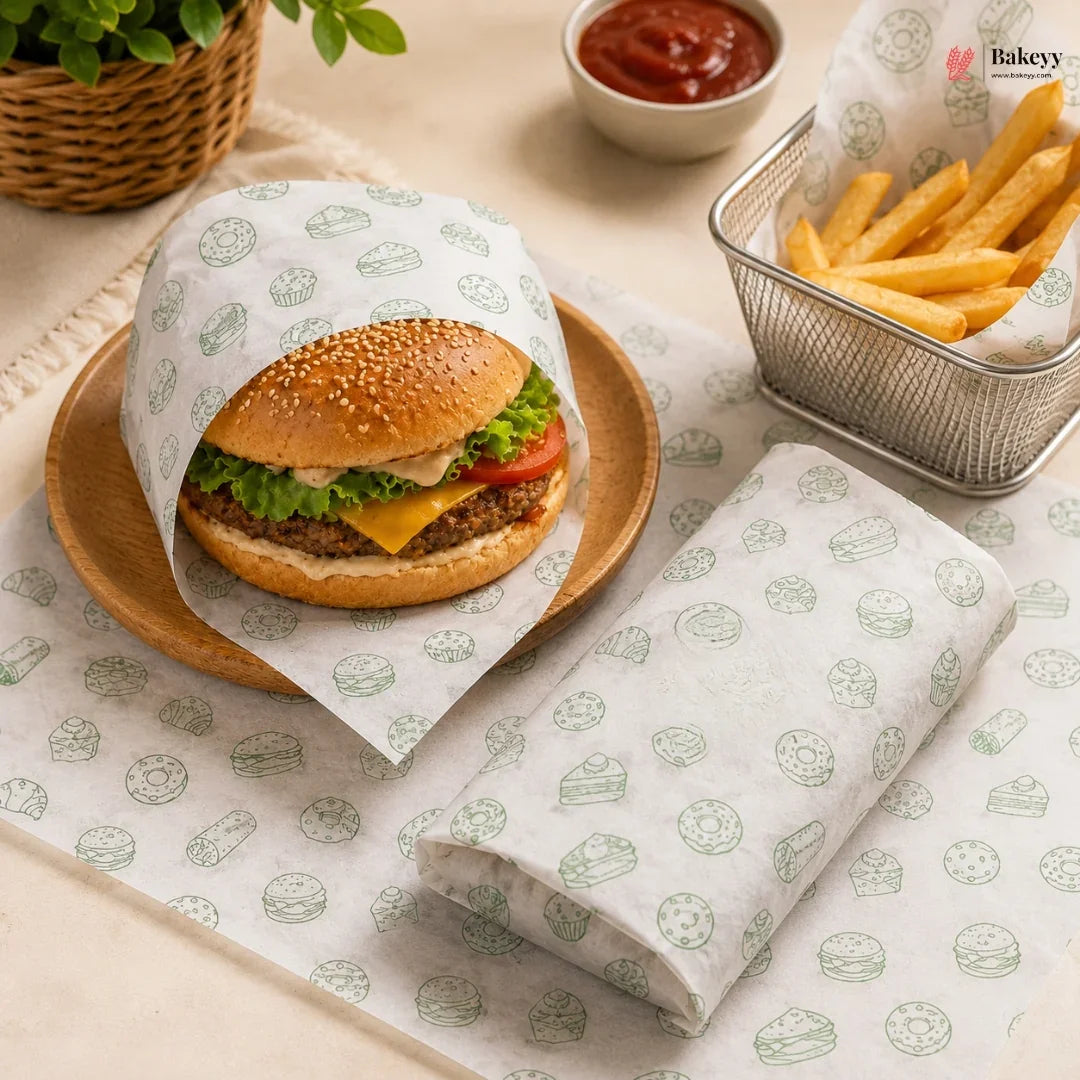 A gourmet hamburger wrapped in branded white paper sleeve with green burger illustrations, served on a wooden plate next to french fries and ketchup, with a matching folded sleeve in the foreground.