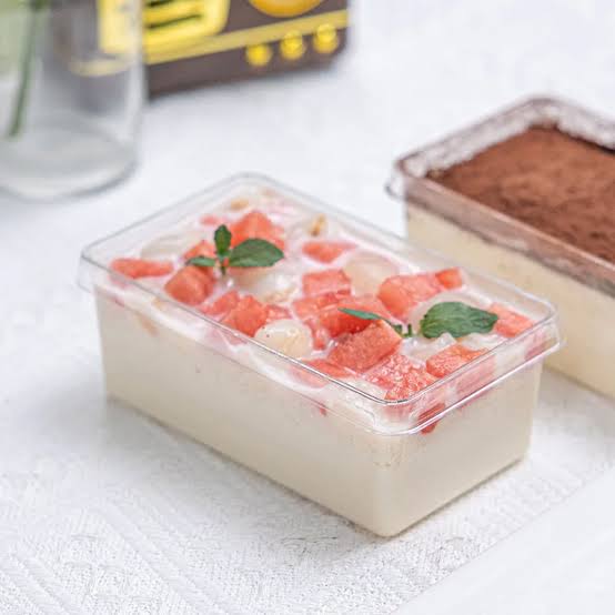 Rectangular container of dessert with fruit pieces on a white surface