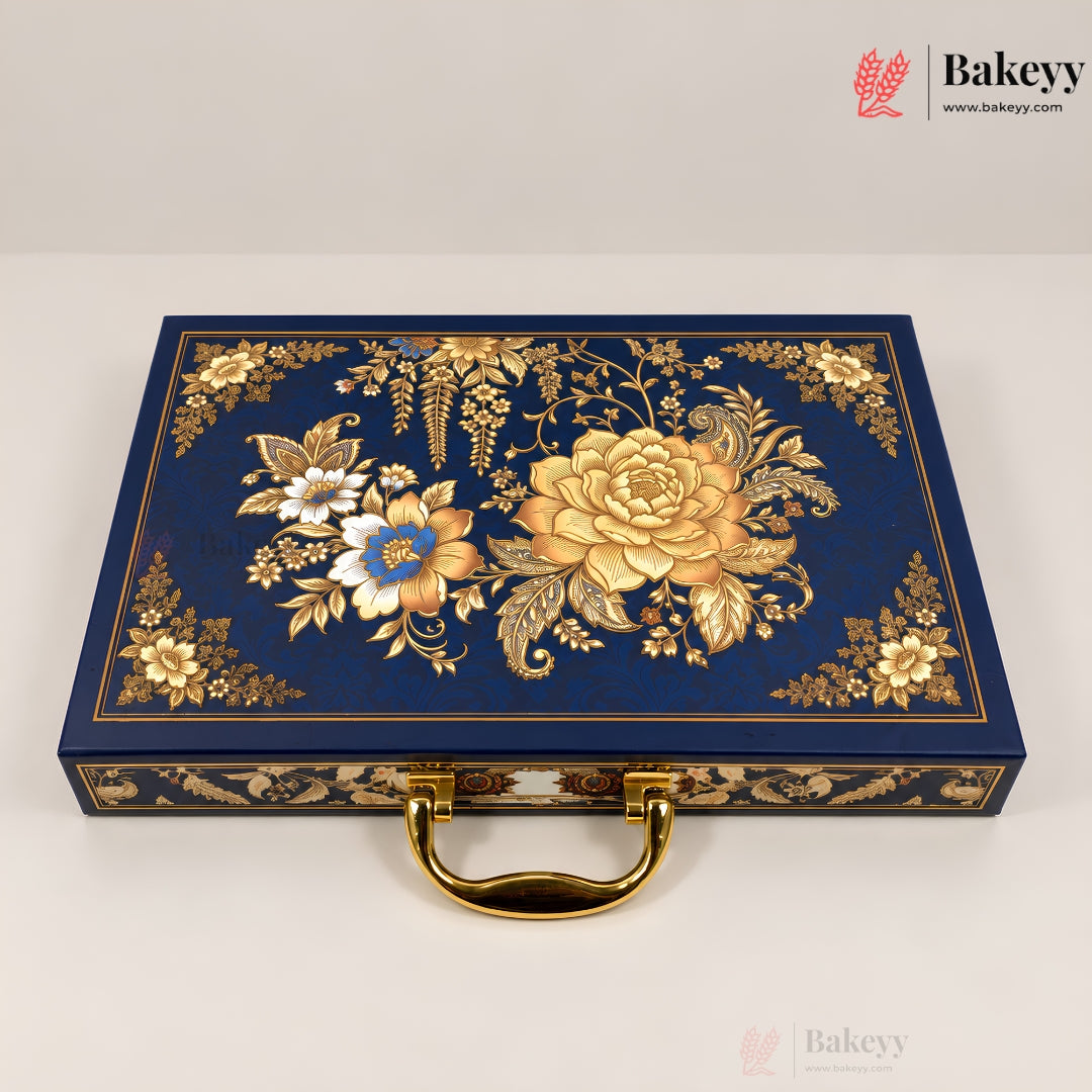 A rectangular navy blue decorative box with ornate gold floral and botanical embossed patterns on the lid, a gold handle, and gold trim along the edges, photographed on a light neutral background. Bakeyy branding is visible in the top-right corner.