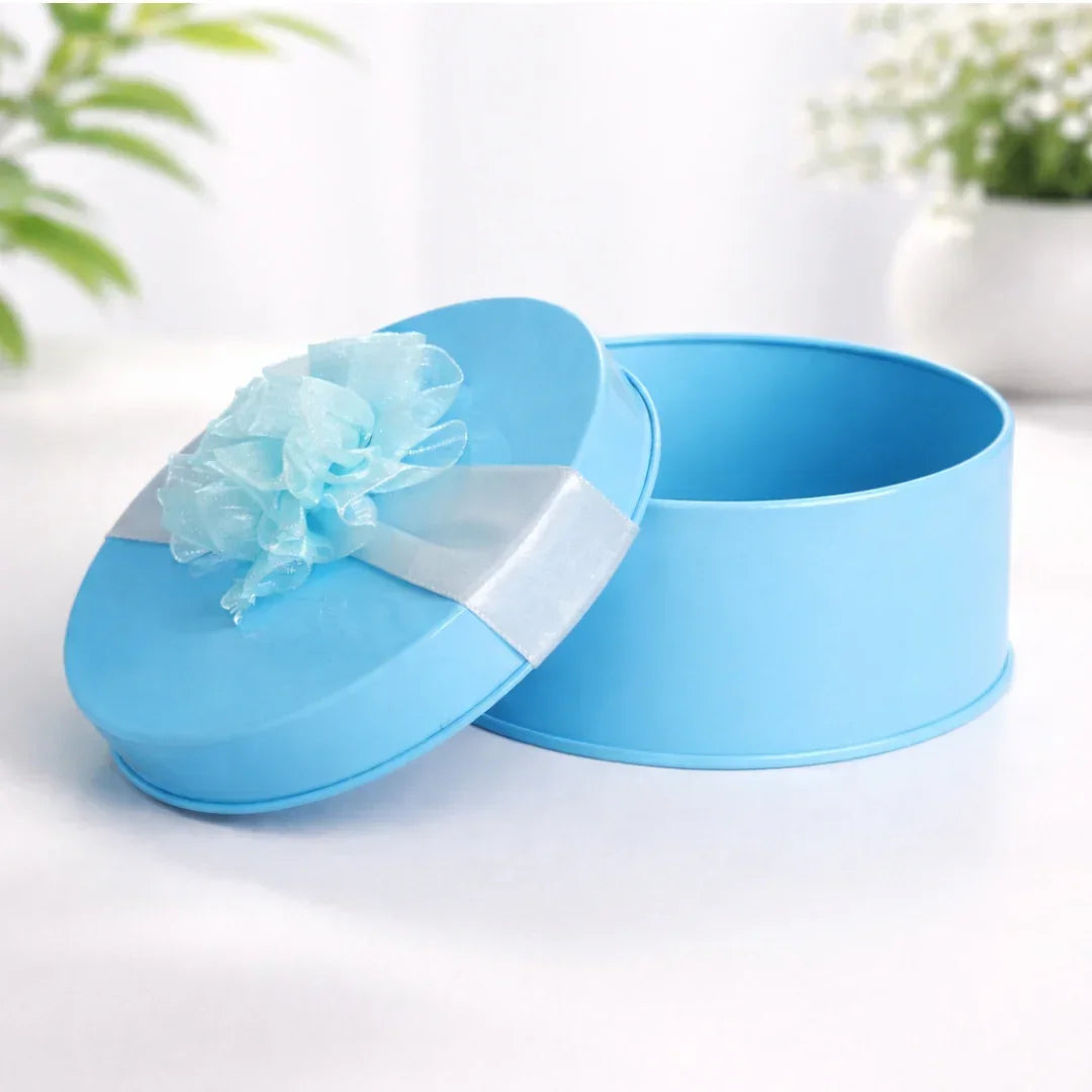 Round blue decorative metal tin box with ribbon flower, ideal for gift packaging from Bakeyy