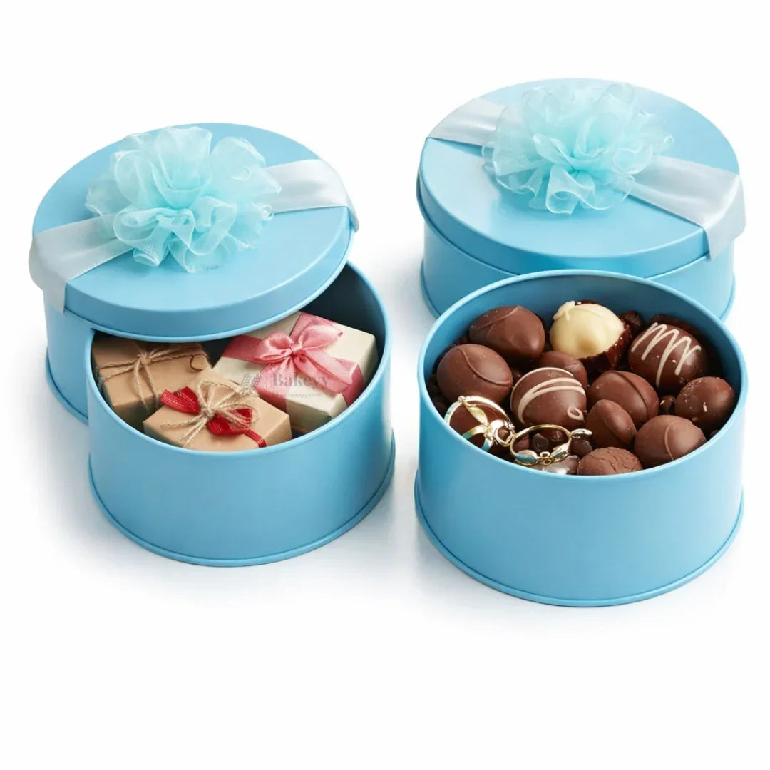 Round blue decorative tin gift boxes with ribbon, filled with chocolates and small presents, Bakeyy gift packaging