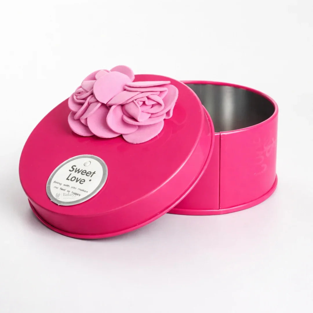 Round pink decorative metal tin box with ribbon flower, ideal for gift packaging from Bakeyy.com