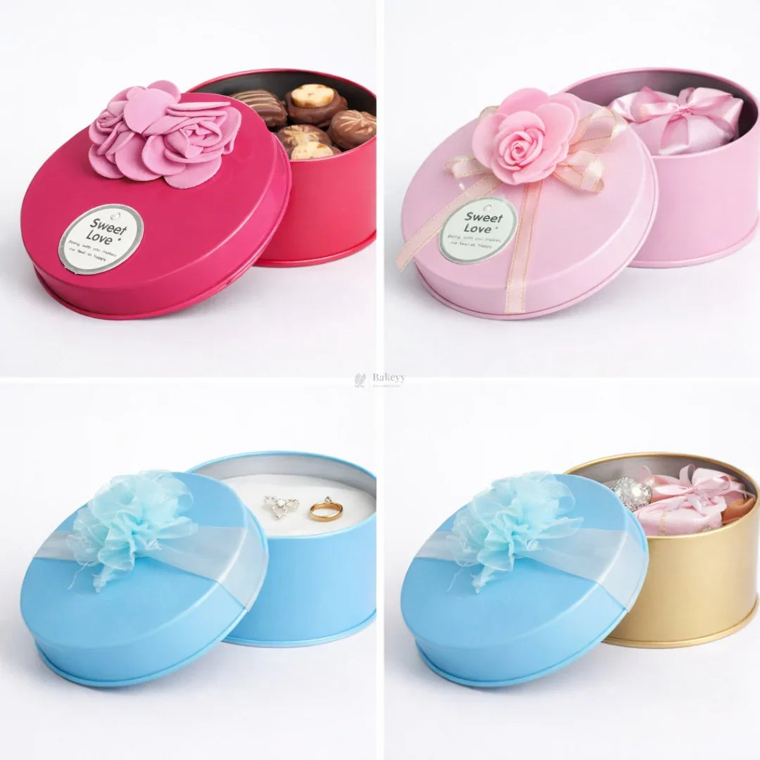 Round decorative metal tin gift boxes with ribbons in pink, blue, and gold from Bakeyy.com