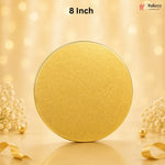 An 8-inch round gold-colored metal tin with a subtle embossed floral pattern, set against a warm, glowing bokeh background with decorative dried flowers and ribbons.