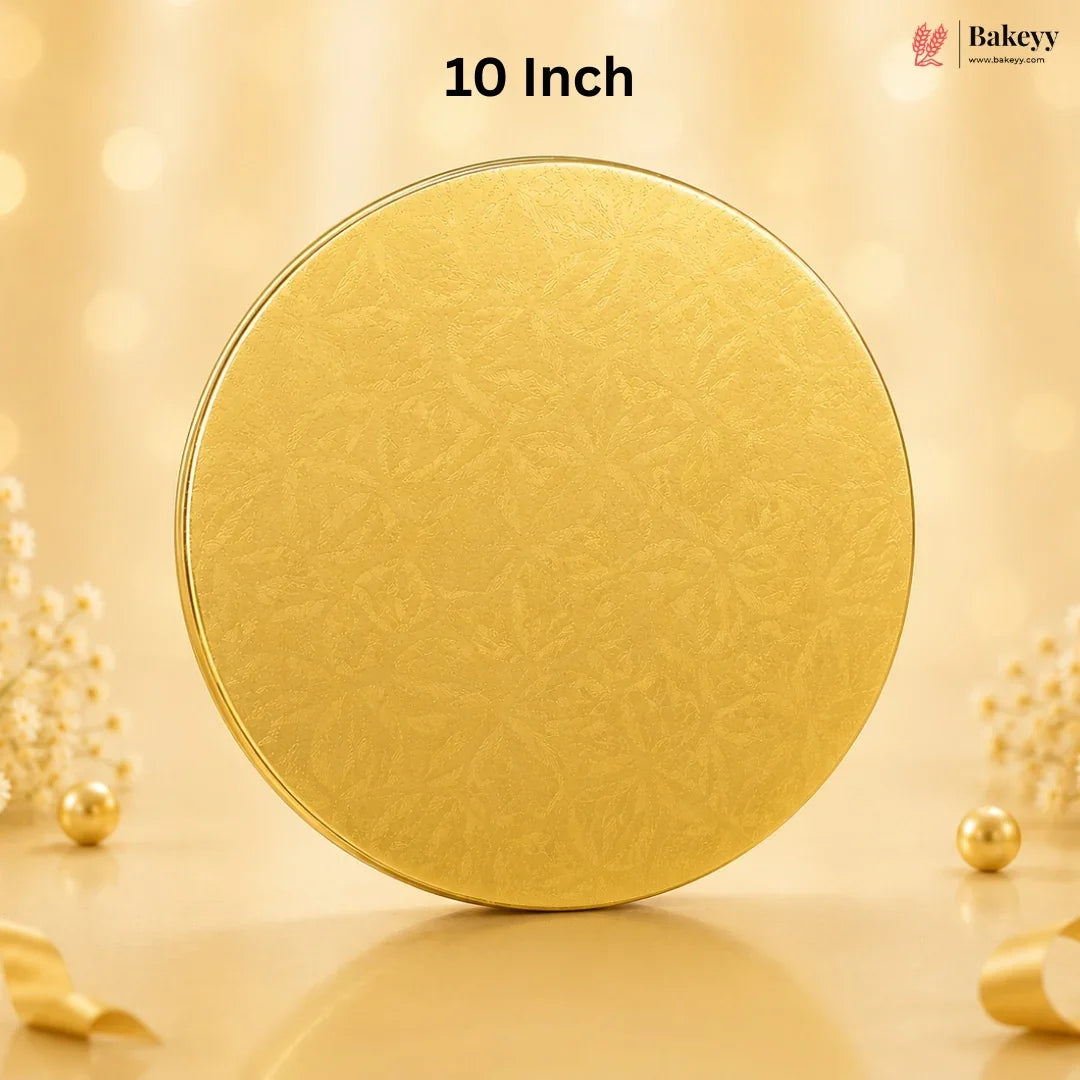 A round gold-colored tin with a subtle embossed floral pattern, standing upright on a reflective surface. The background is a warm, soft beige with bokeh lights and decorative pearl-like flowers.