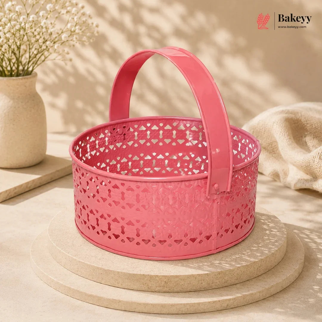 Pink decorative basket with a handle on a beige surface, featuring the Bakeyy brand.