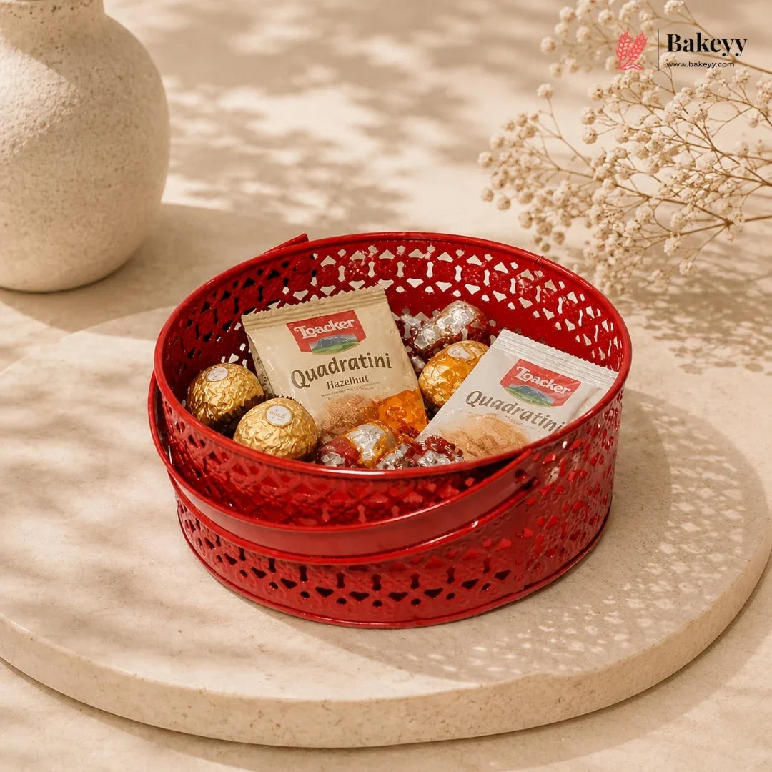 Red decorative basket with snacks and cookies on a beige surface, featuring the Bakeyy brand.