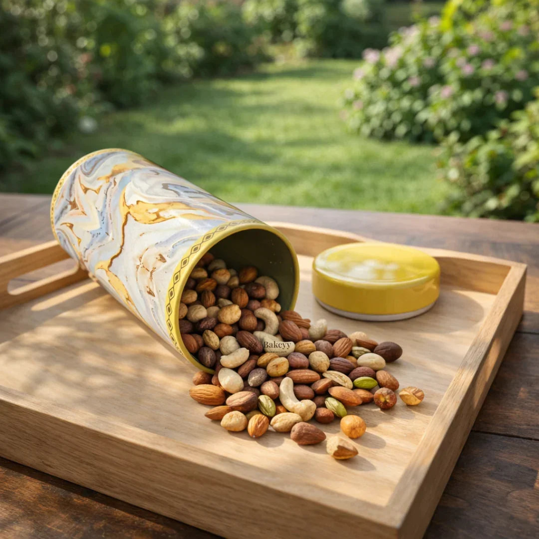 Round metal tin box with marbled design, filled with mixed nuts on a wooden tray outdoors