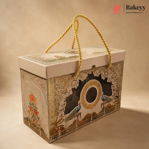 An ornate rectangular gift box with a cream-colored lid and sides, decorated with intricate gold, blue, and orange floral and bird illustrations. The box features a central cutout window and is equipped with a thick gold rope handle, set against a warm beige background.