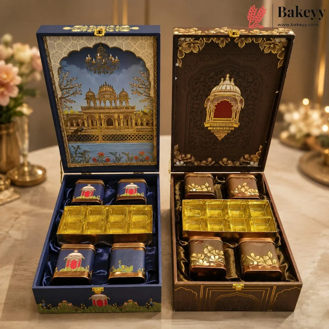 Two ornate gift boxes for tea or spices are shown open on a table. The left box is navy blue with gold detailing and an illustrated palace scene on the lid, containing four small blue containers and a gold tray.