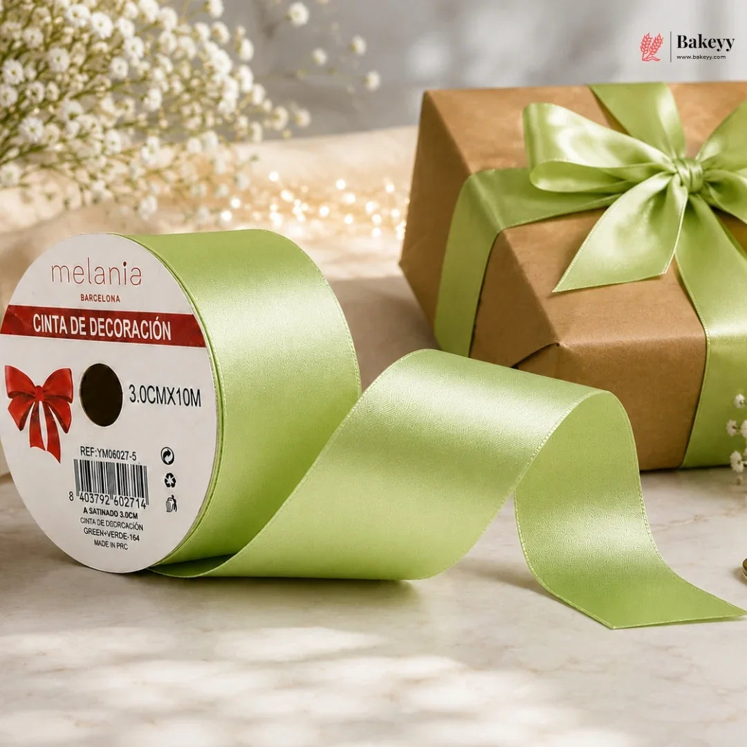 Green ribbon with a gift box and baby's breath flowers on a light surface