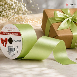 Green ribbon with a gift box and baby's breath flowers on a light surface