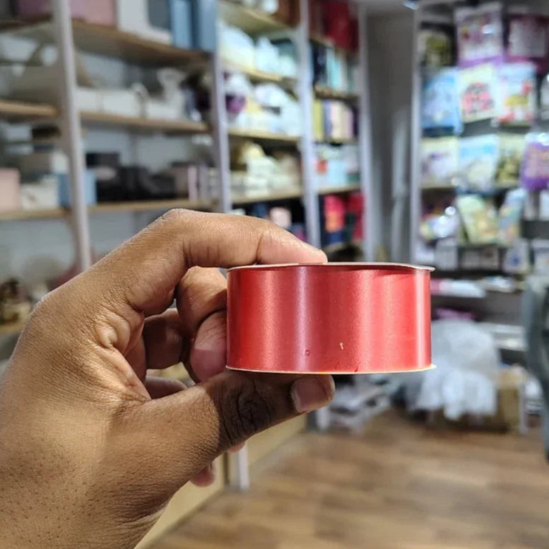 Hand holding a red cylindrical object with shelves and products in the background