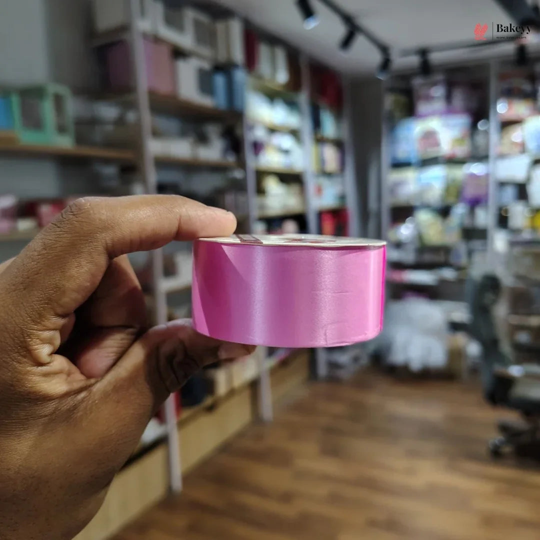 Hand holding a pink roll of tape in a store setting