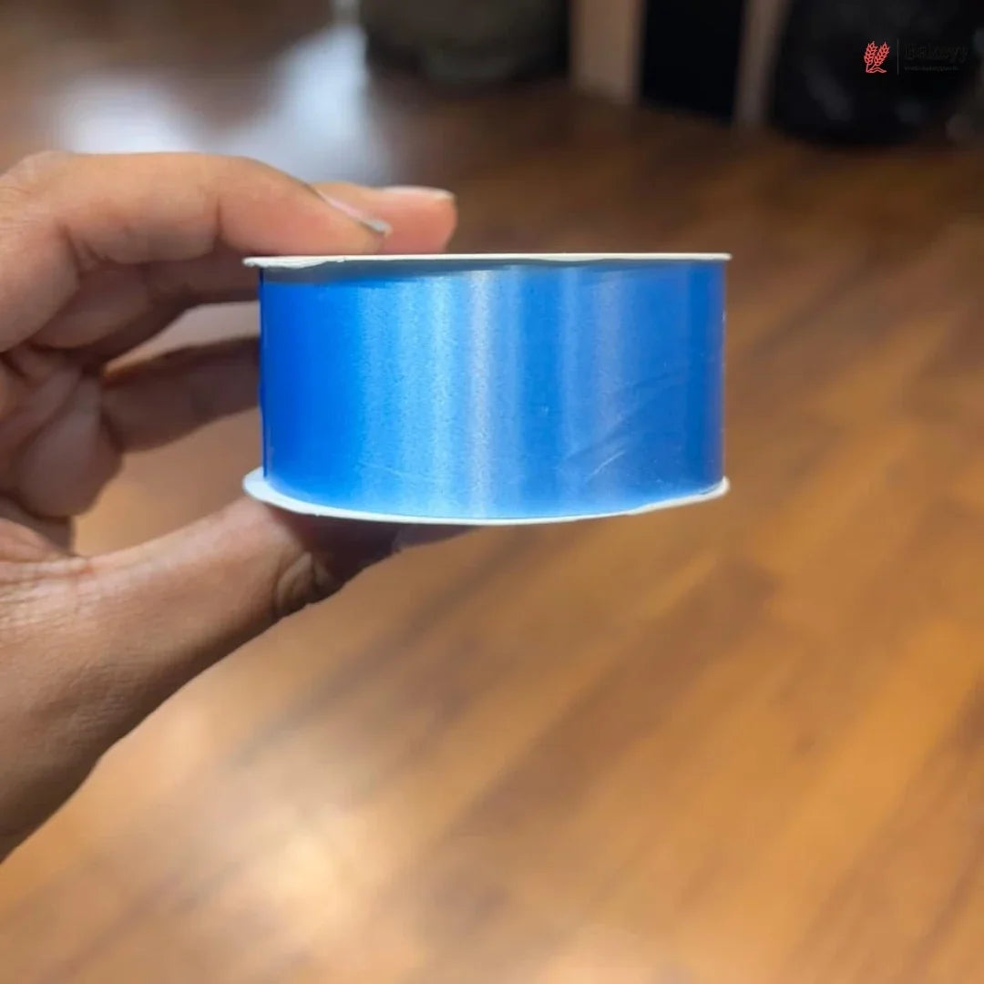 Hand holding a roll of blue tape on a wooden surface