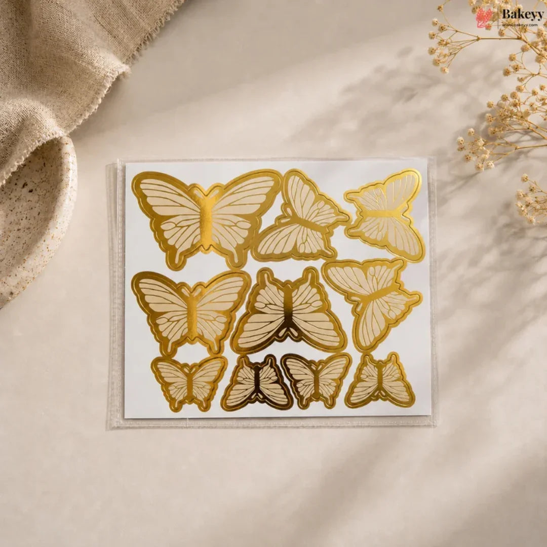 Set of gold butterfly-shaped cookie cutters on a beige surface with a textured fabric and dried flowers in the background.