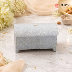 Small decorative box with a textured surface on a marble background with flowers and Bakeyy branding.