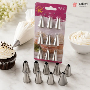 A 9-piece set of stainless steel icing tip nozzles displayed on a marble surface, with some tips arranged in front of their pink retail packaging. A piping bag with white icing, a decorated cupcake, and a bowl of icing are styled around the product.