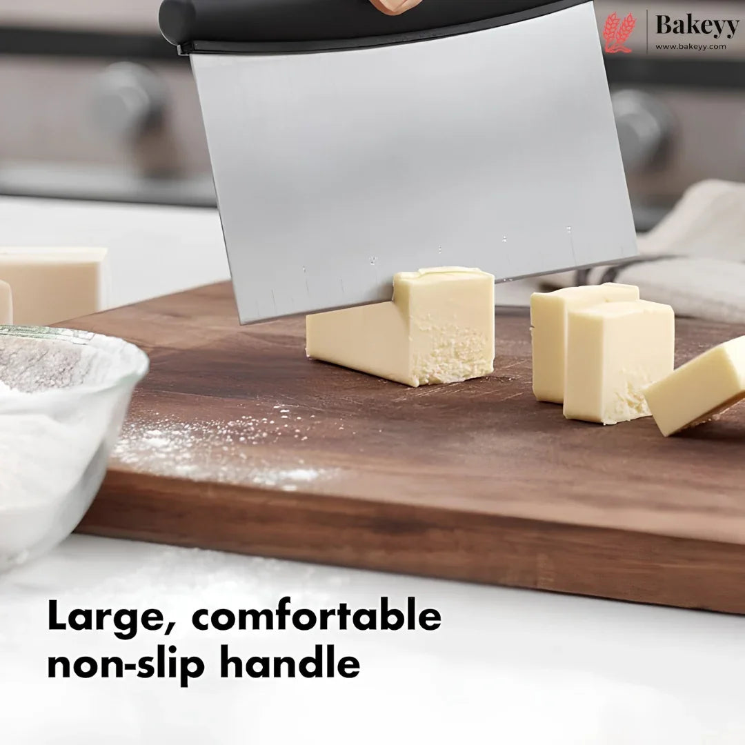 A large commercial-style pastry scraper or bench scraper with a non-slip handle, shown in use on a wooden cutting board slicing butter. The text overlay at the bottom reads 'Large, comfortable non-slip handle'.