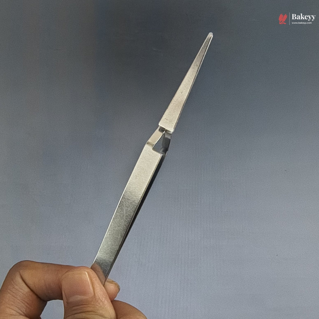 Metal tweezers held by a hand against a gray background