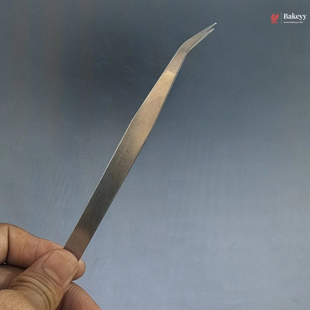 Metallic tweezer held by a hand against a blue background with 'Bakeys' branding.