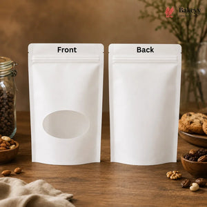 Two blank white stand-up pouches labeled 'Front' and 'Back' with a die-cut oval window on the front, displayed on a wooden table with baking ingredients and cookies in the background.