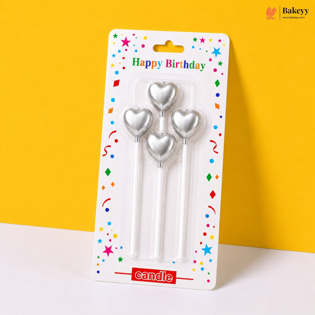Three silver heart-shaped candles in packaging with 'Happy Birthday' text on a yellow background
