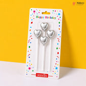 Three silver heart-shaped candles in packaging with 'Happy Birthday' text on a yellow background