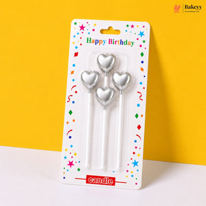 Three silver heart-shaped candles in packaging with 'Happy Birthday' text on a yellow background