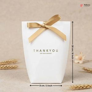 White gift box with gold ribbon and 'THANKYOU' text, placed on a beige surface with wheat stalks.