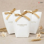 Three white gift boxes with gold ribbons and 'THANKYOU' text on a beige background.