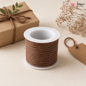 Spool of brown twine on a white surface with a gift box and decorative elements.