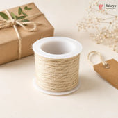 Spool of twine on a white surface with a gift box and decorative elements.