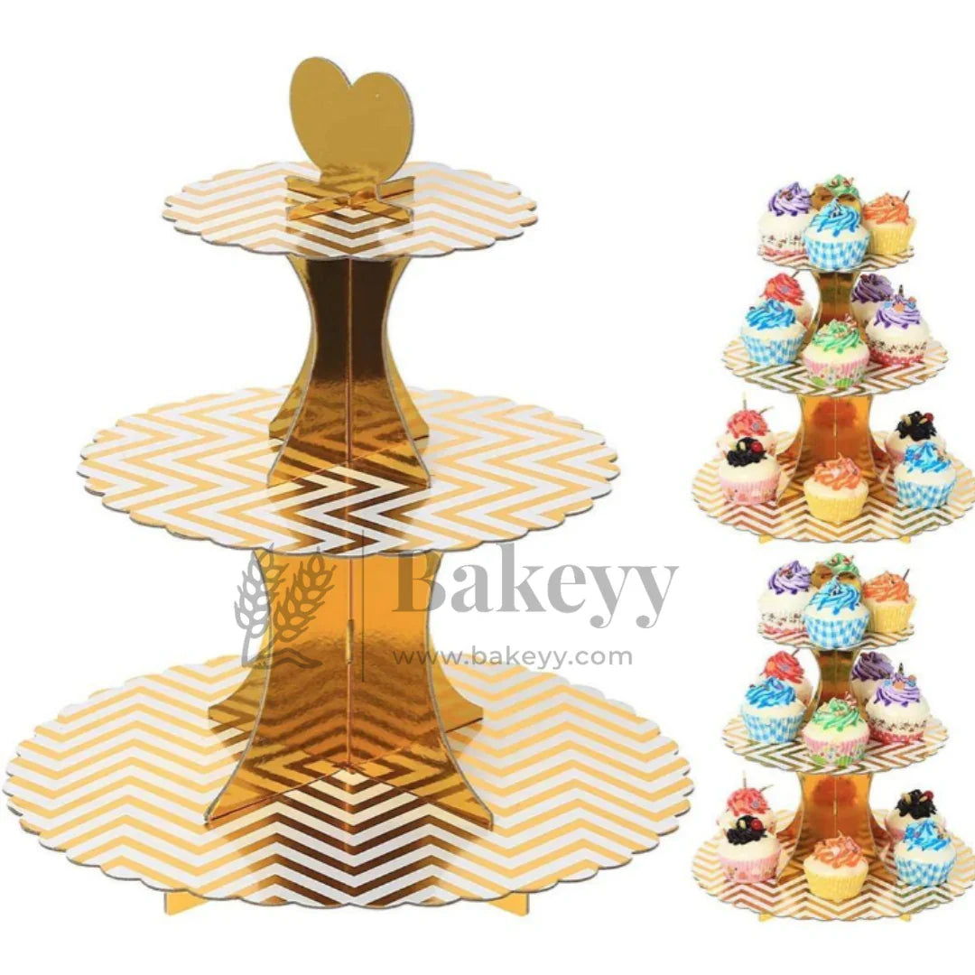 Three-tiered gold and white chevron patterned cupcake stand with colorful cupcakes on a white background.