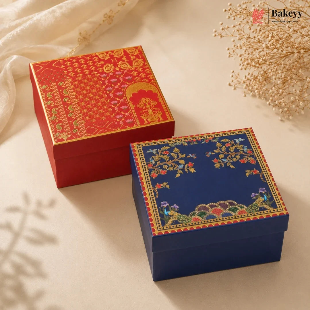 Two decorative gift boxes on a cream fabric background, one red with gold patterns and one navy blue with multicolor floral and peacock motifs. A Bakeey logo watermark is visible in the top right.