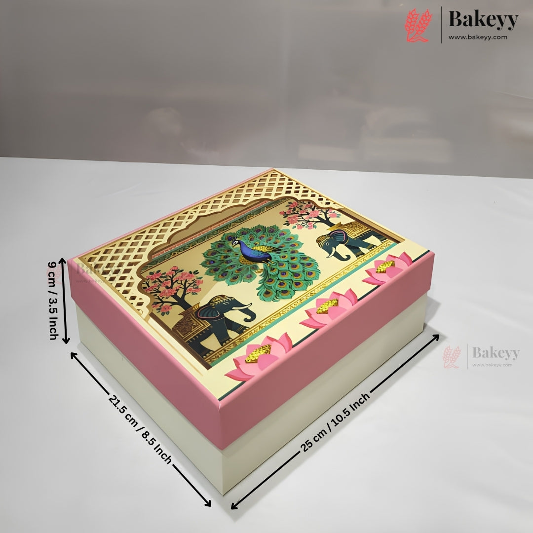 A decorated rectangular cake or gift box with a pink and cream base and a detailed top panel showing a peacock, elephants, and floral motifs. Black dimension arrows and text indicate measurements of 26 cm by 22 cm by 9 cm.