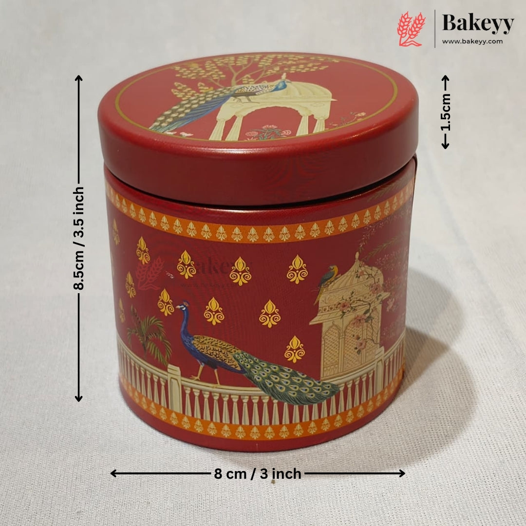A red cylindrical metal cake tin with a lid, decorated with gold and multicolor peacock and architectural motifs. Black dimension arrows and text indicate a height of 8.