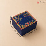 A square navy blue decorative gift box with colorful floral and bird motifs on the lid, shown on a beige background with black dimension arrows and text indicating 15.5 cm by 10 cm by 15.