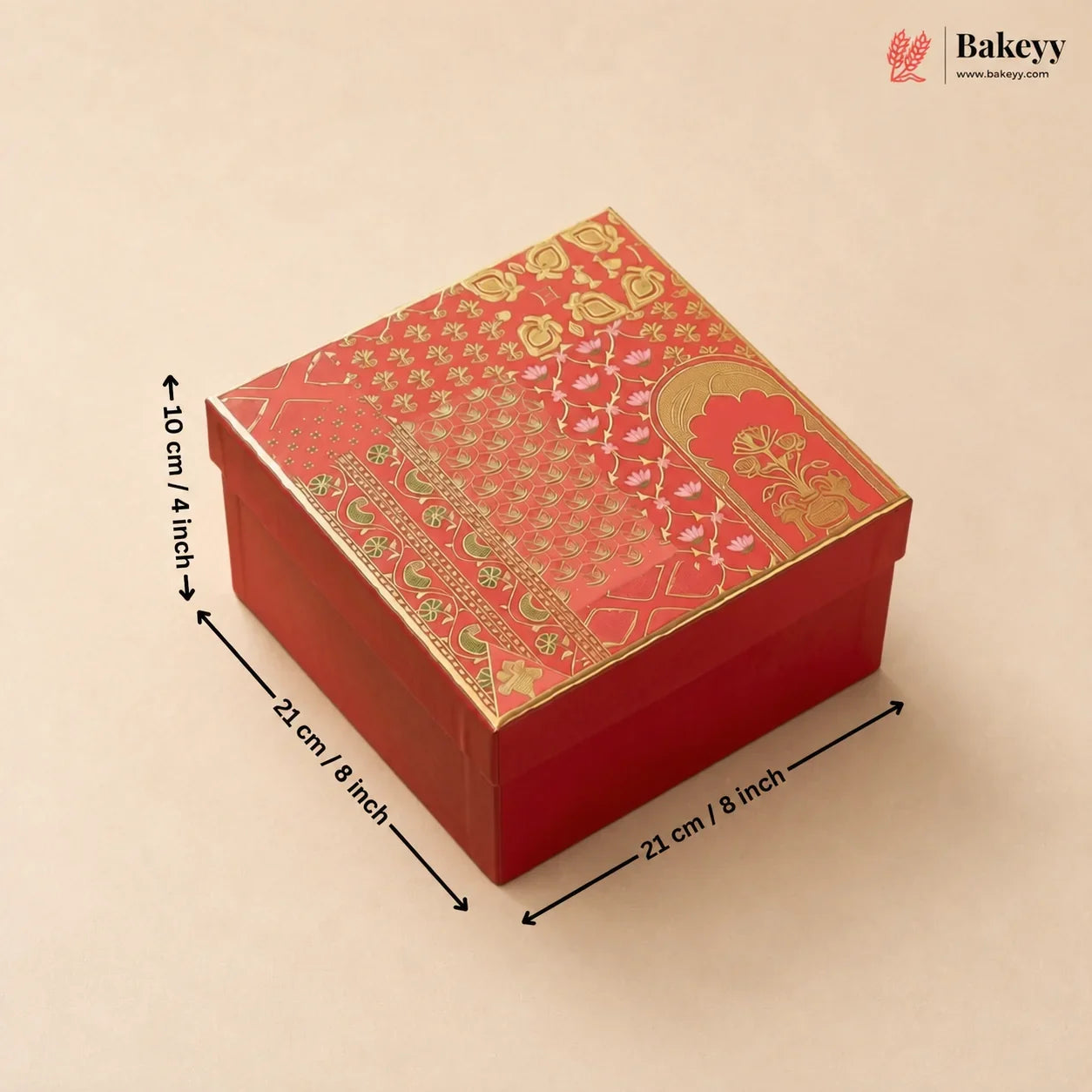 A red square gift box with ornate gold and green patterned detailing on the lid, shown on a beige background with dimension arrows and text indicating measurements of 21 cm by 21 cm by 10 cm.