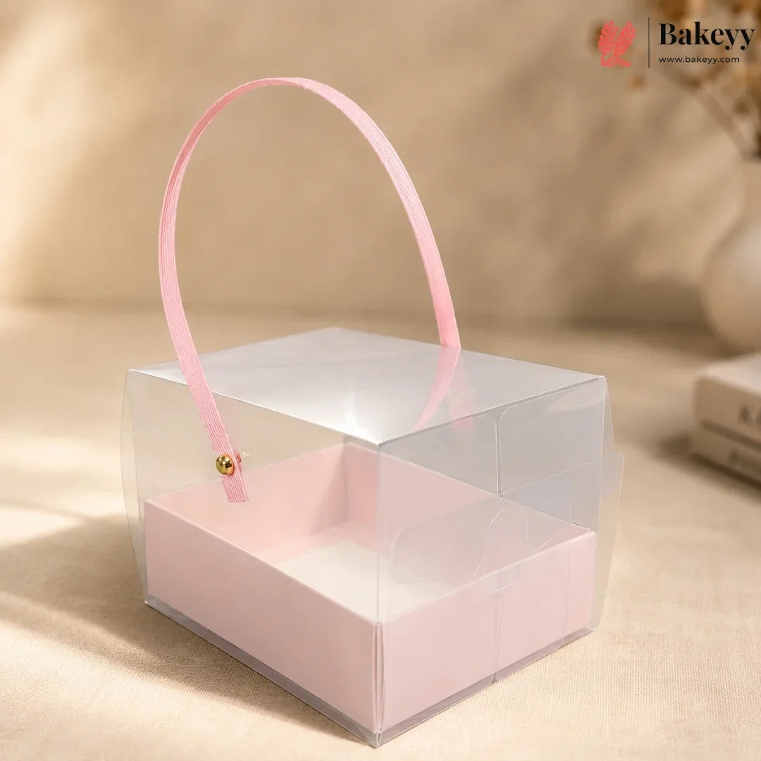 Clear gift box with pink handle and interior on a beige background, featuring the Bakeyy brand.
