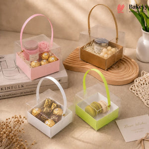 Four transparent gift boxes with handles containing various items on a beige surface.